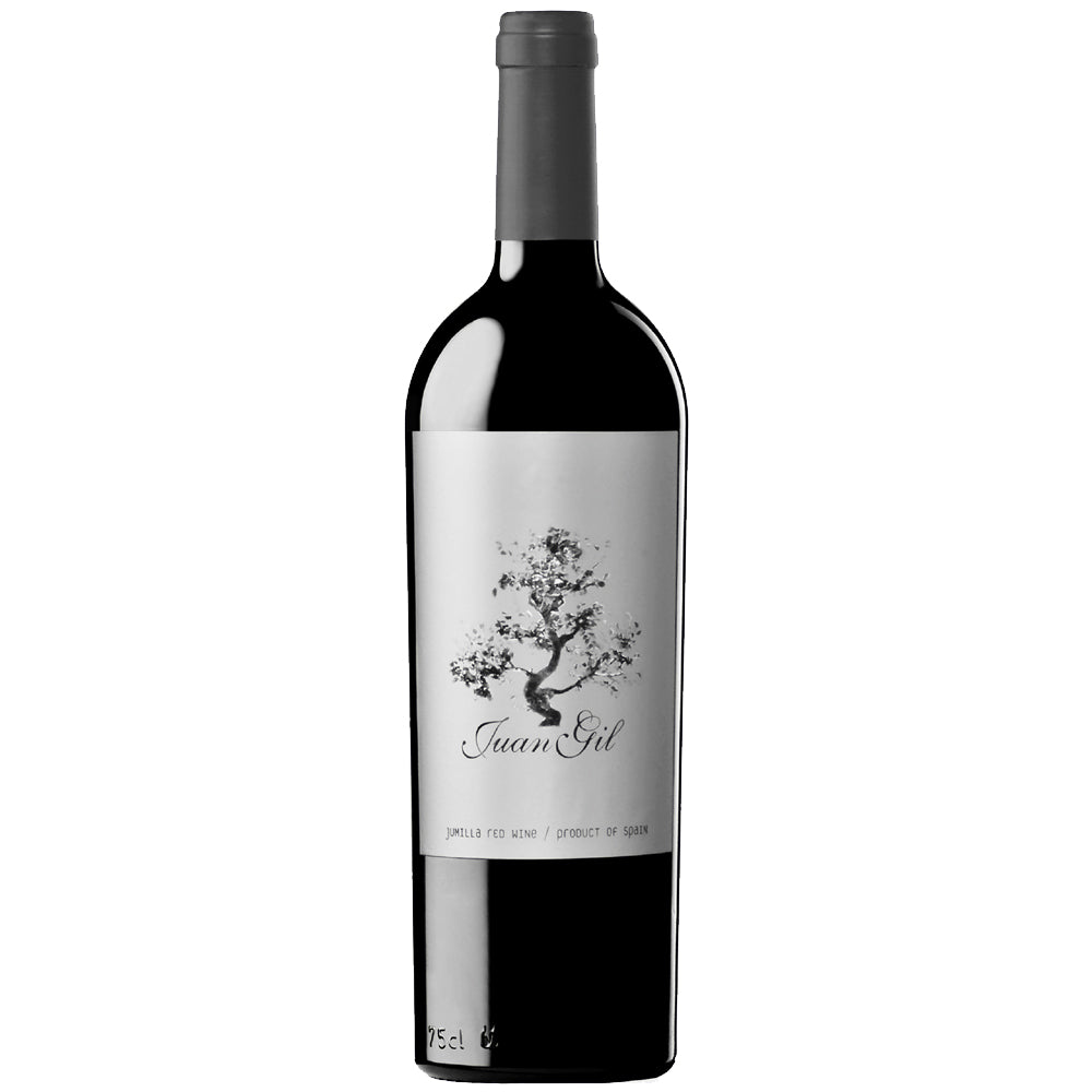 A bottle of Juan Gil Silver Label Monastrell red wine with a black glass body, dark grey capsule, and a white label featuring a black tree illustration and the brand name 'Juan Gil'.