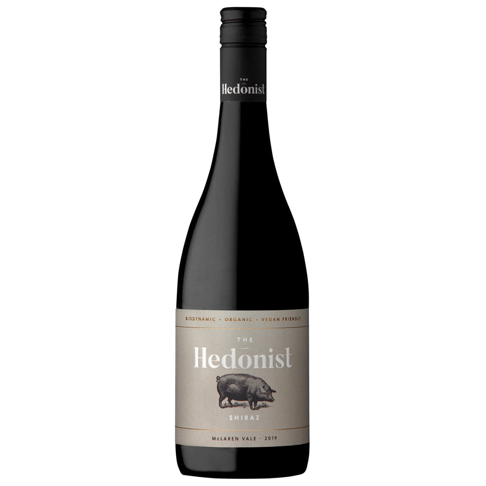 A bottle of The Hedonist Shiraz red wine. It has a grey label with red and white writing and the image of a pig. It has a black screw cap.