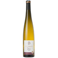 A bottle of Turckheim Grand Cru Brand Riesling white wine, featuring a pale golden-yellow liquid inside a clear glass bottle with a black and gold foil top and a white label.