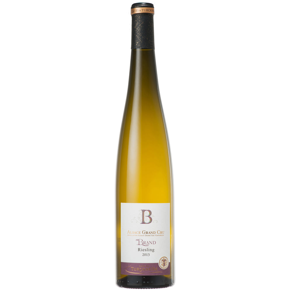 A bottle of Turckheim Grand Cru Brand Riesling white wine, featuring a pale golden-yellow liquid inside a clear glass bottle with a black and gold foil top and a white label.